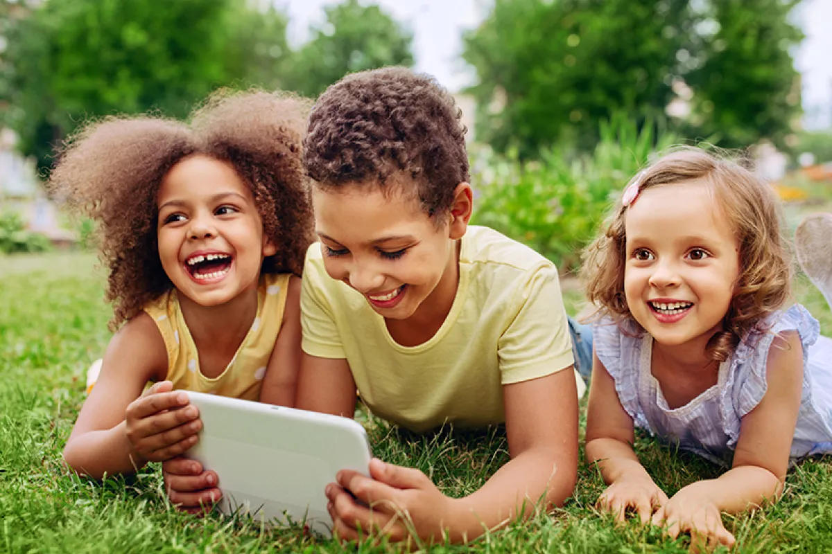 Image of smiling children looking at a tablet